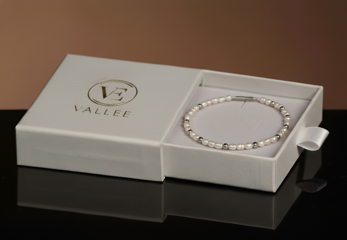 Offene Vallée Schmuckbox mit feinem Perlenarmband aus weißen Zuchtperlen und silberfarbenen Zwischenperlen.